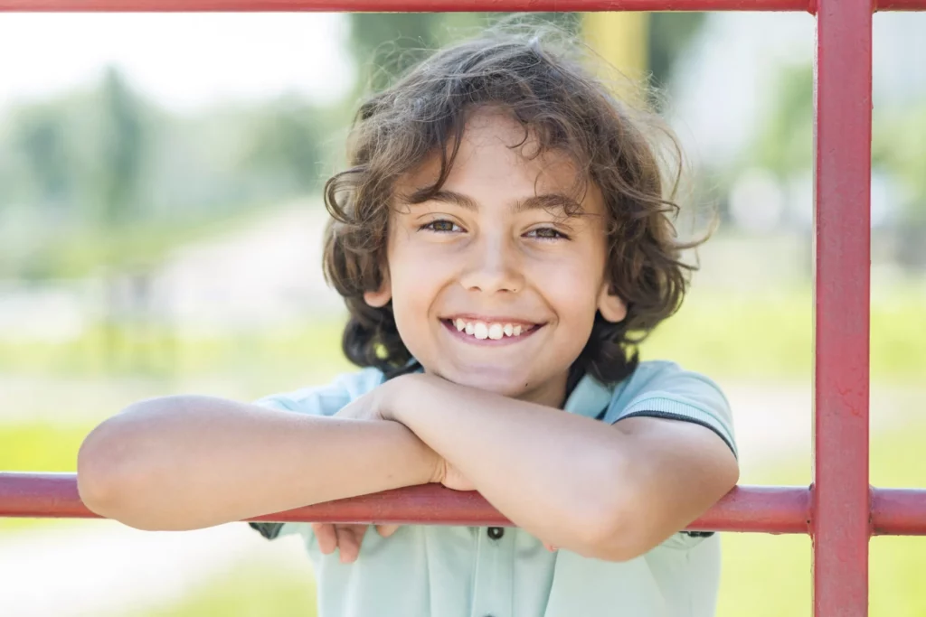 Smiling boy leaning on a playground railing
