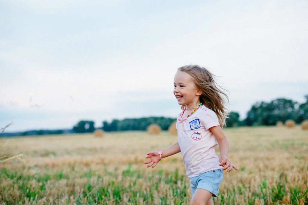 Happy girl running through a grassy field